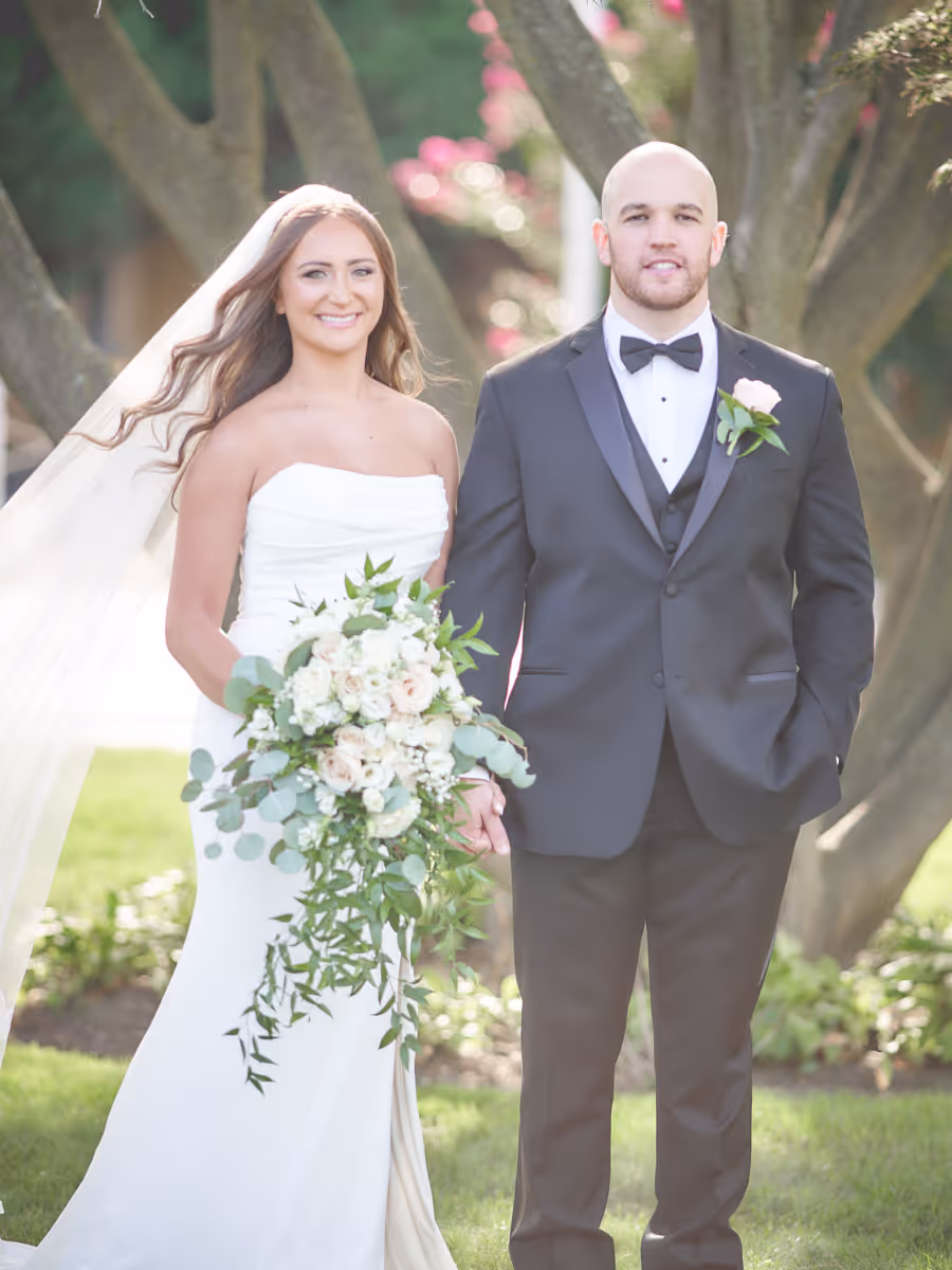 Bride and groom portrait with a cascading white and greenery bouquet