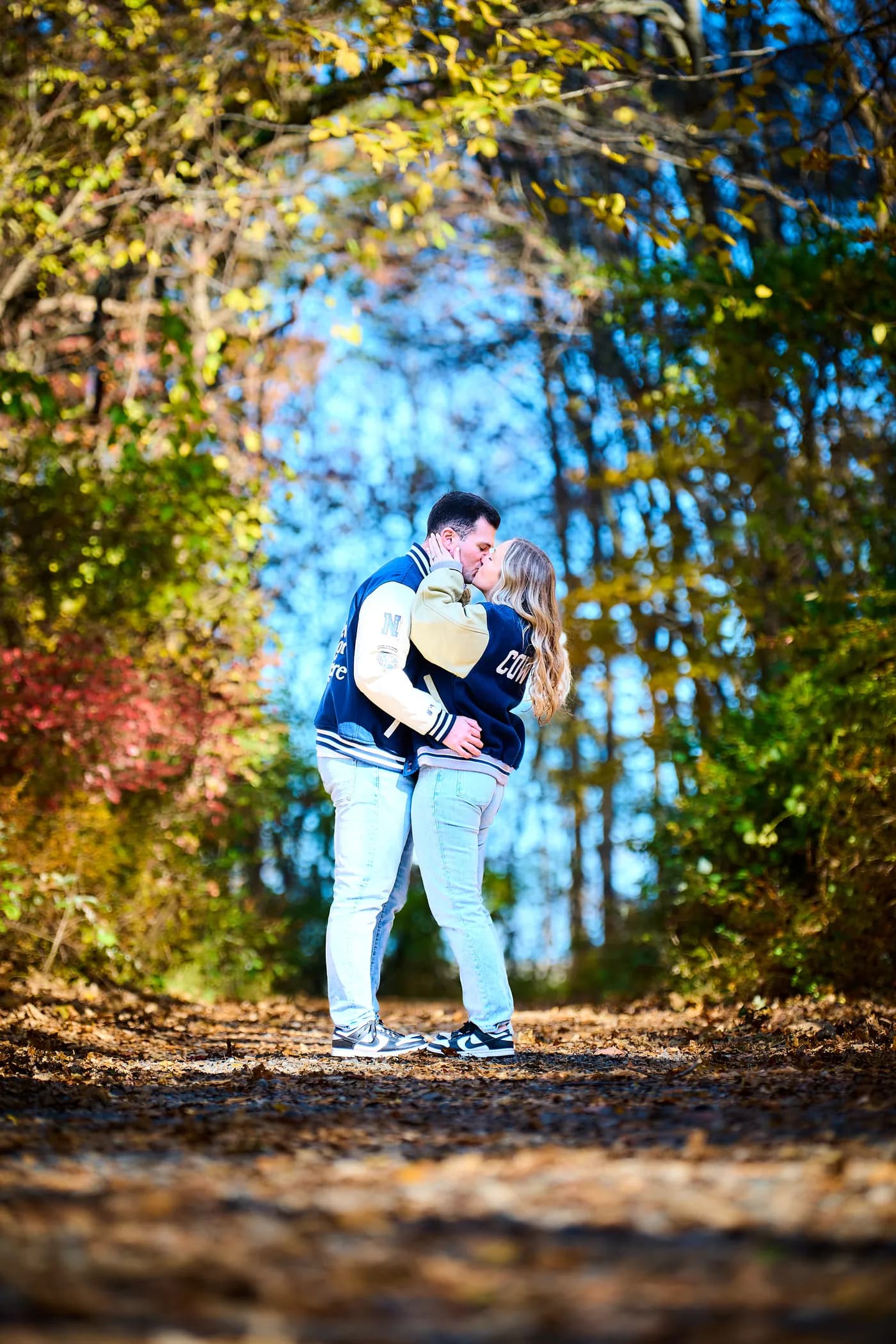 Couple kissing among autumn foliage in cool evening light