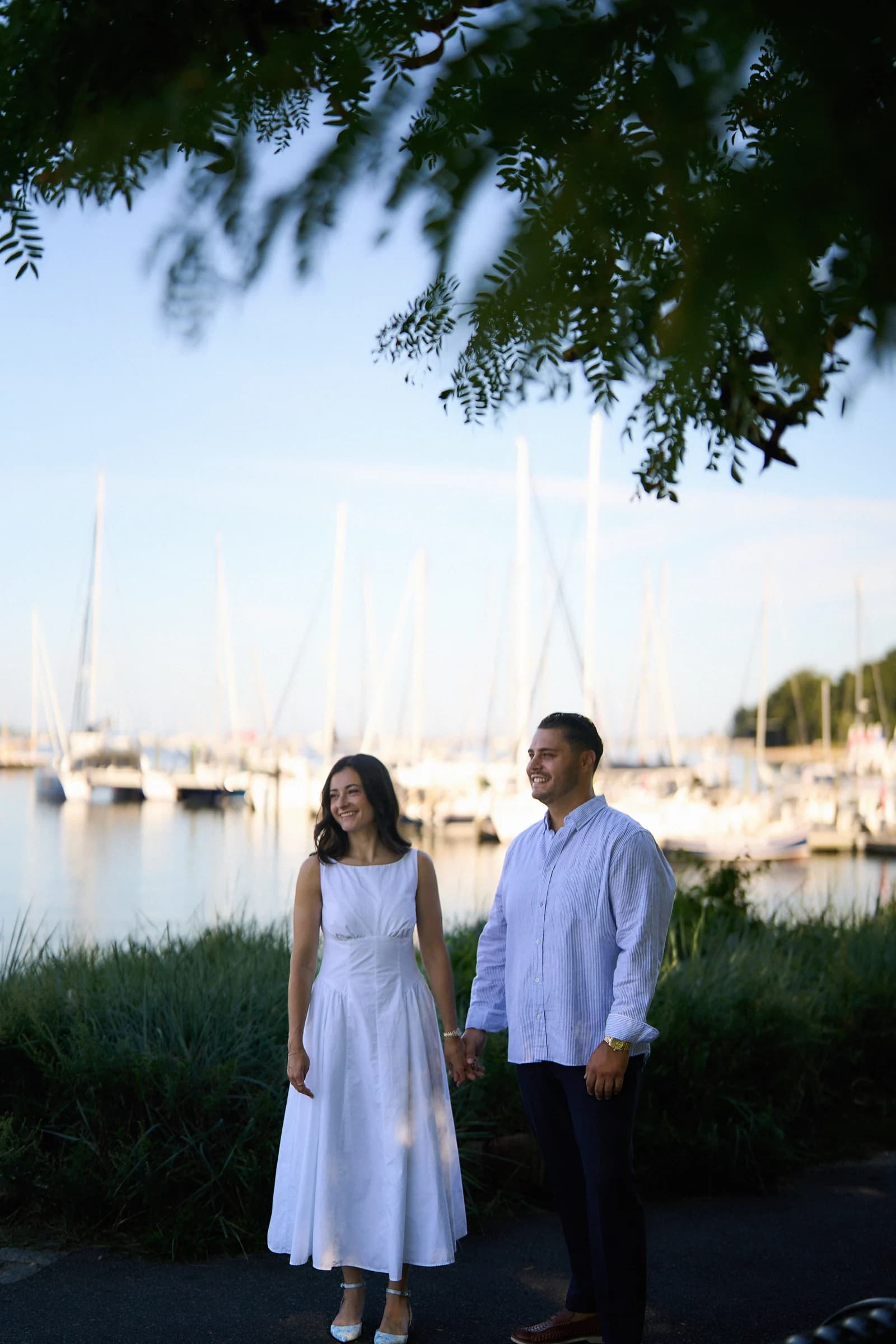 Elizabeth and Rocco holding hands beside the sailboats at Port Jefferson Harbor