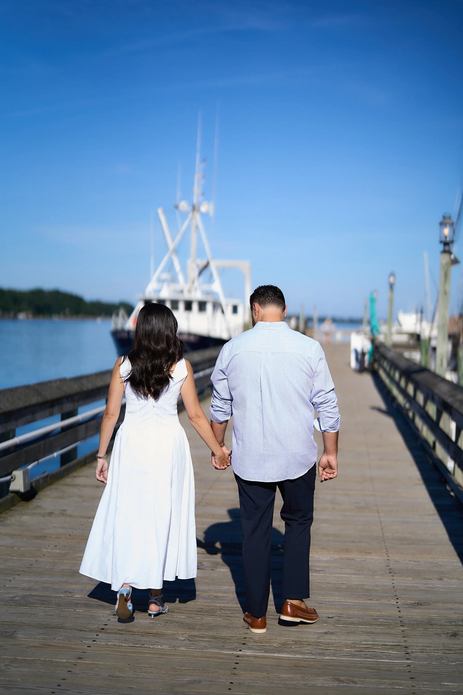 Elizabeth and Rocco walk hand in hand down the pier at Port Jefferson Harbor