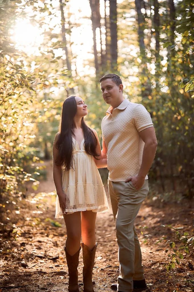 Couple on a forest path with golden light filtering through the trees