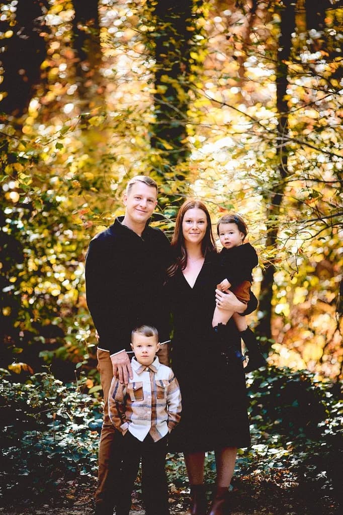Family of four among golden autumn trees