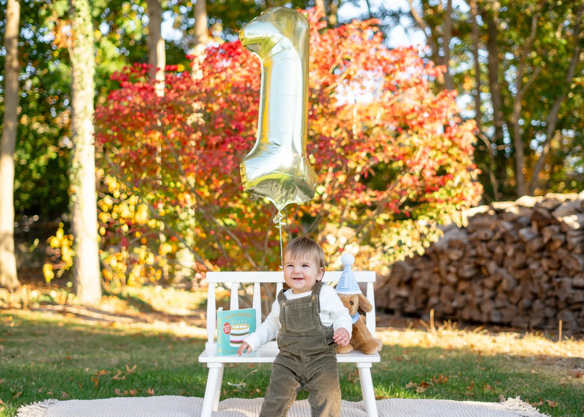One year old at a first birthday session with a gold balloon and autumn color