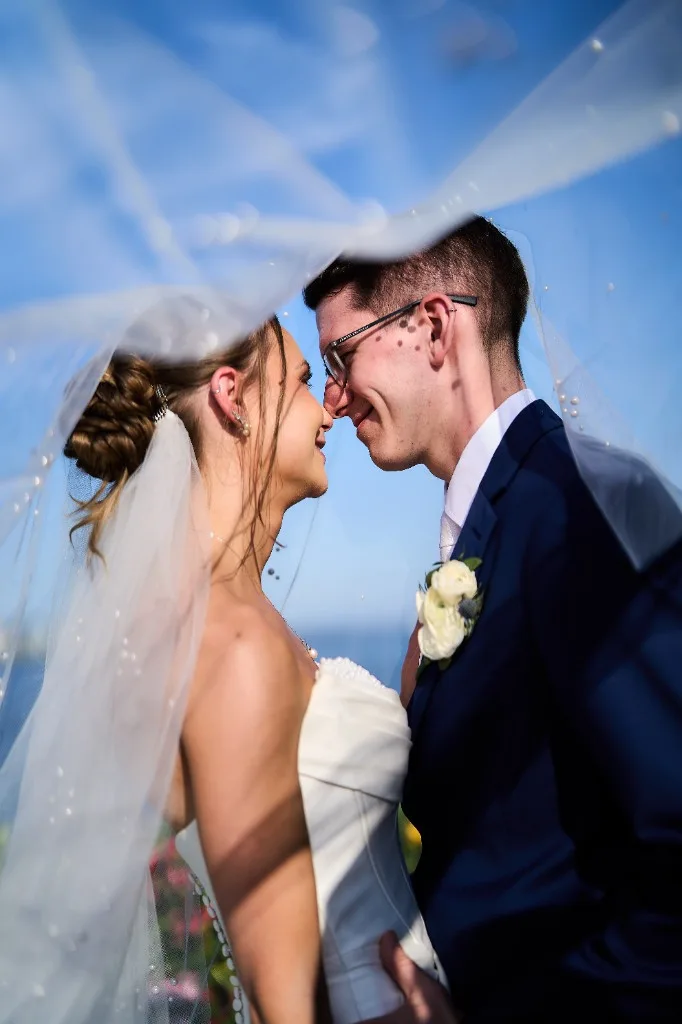 Melanie and Matthew under her pearl-trimmed veil, about to kiss