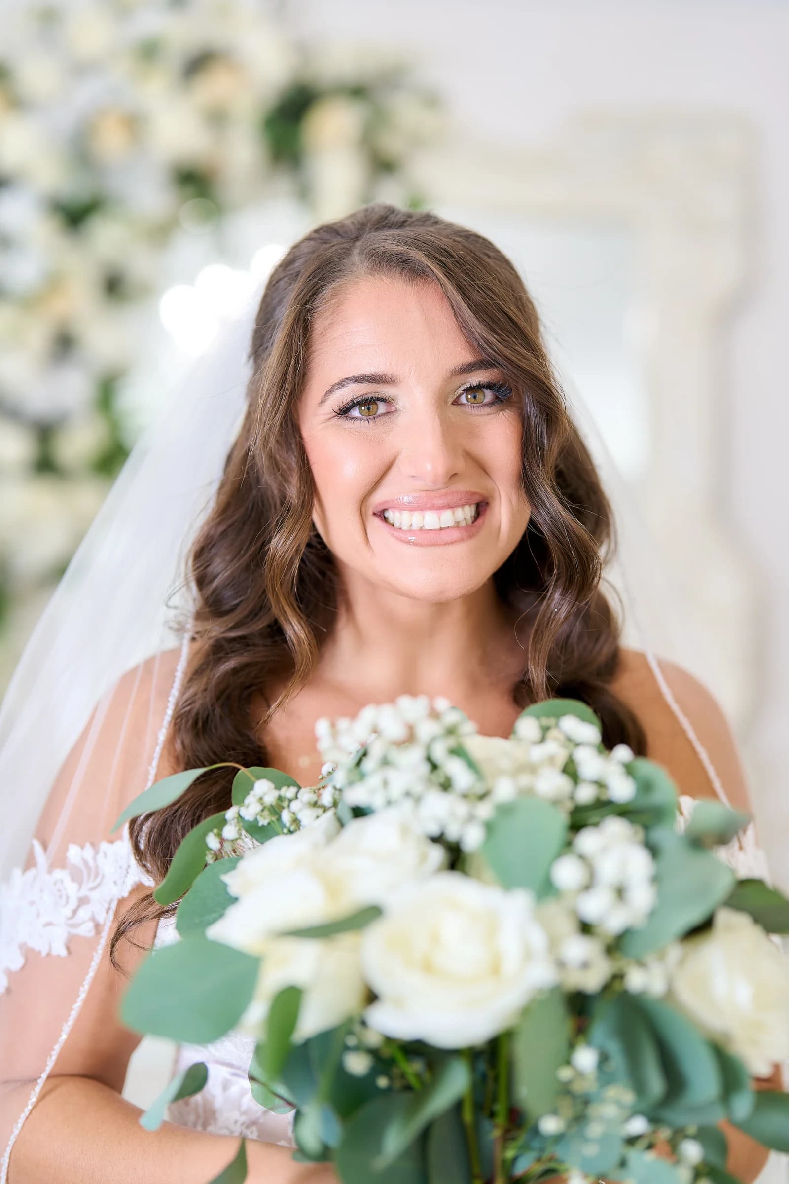 Amanda smiling with her white rose and eucalyptus bouquet