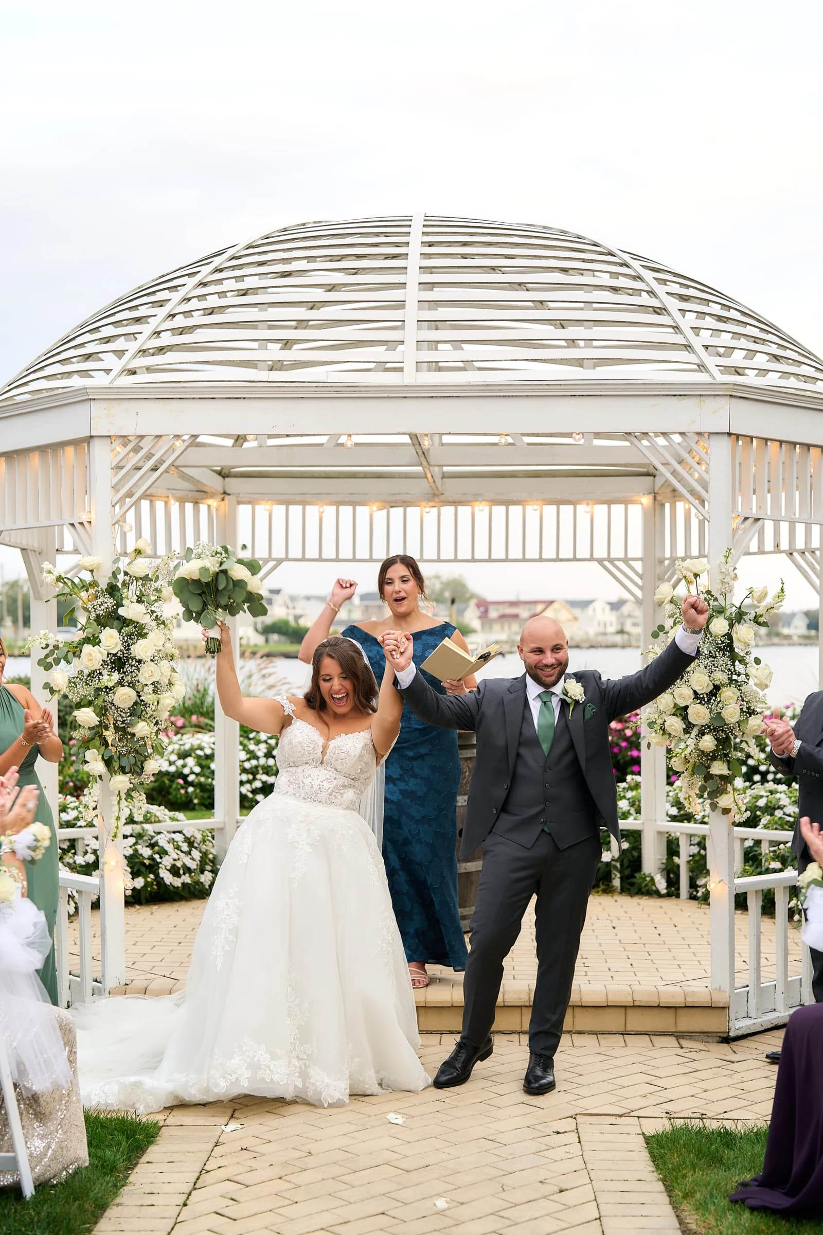Amanda and Gabriele celebrating just married under the Riviera gazebo, arms raised