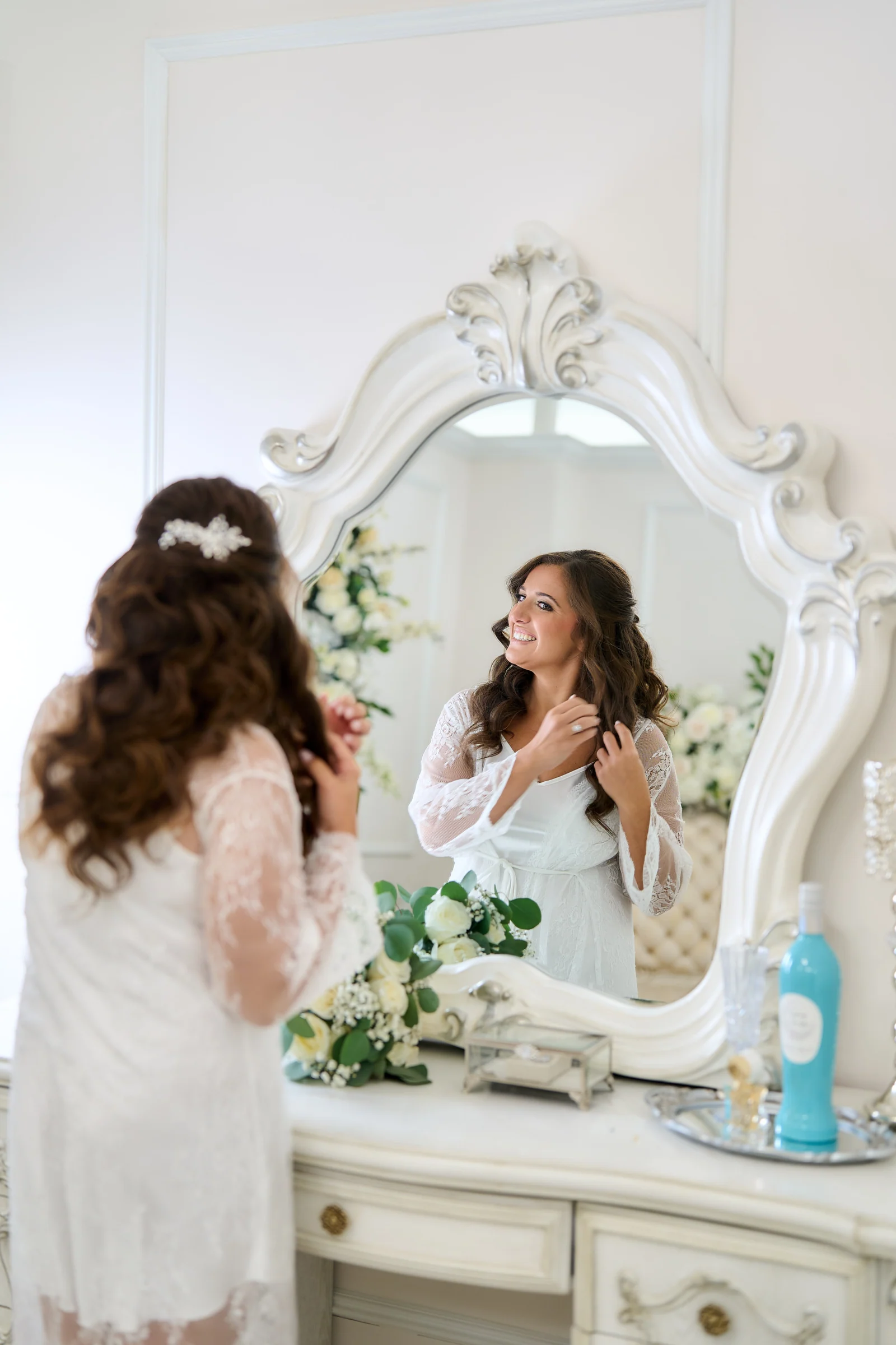 Vineyard rows against a bayfront terrace, Amanda smiling in the mirror as she finishes her hair in a lace robe