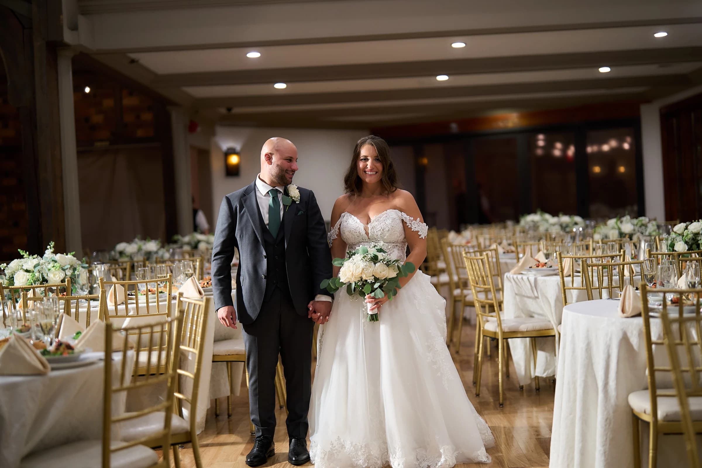 Amanda and Gabriele holding hands in the reception hall before guests arrive