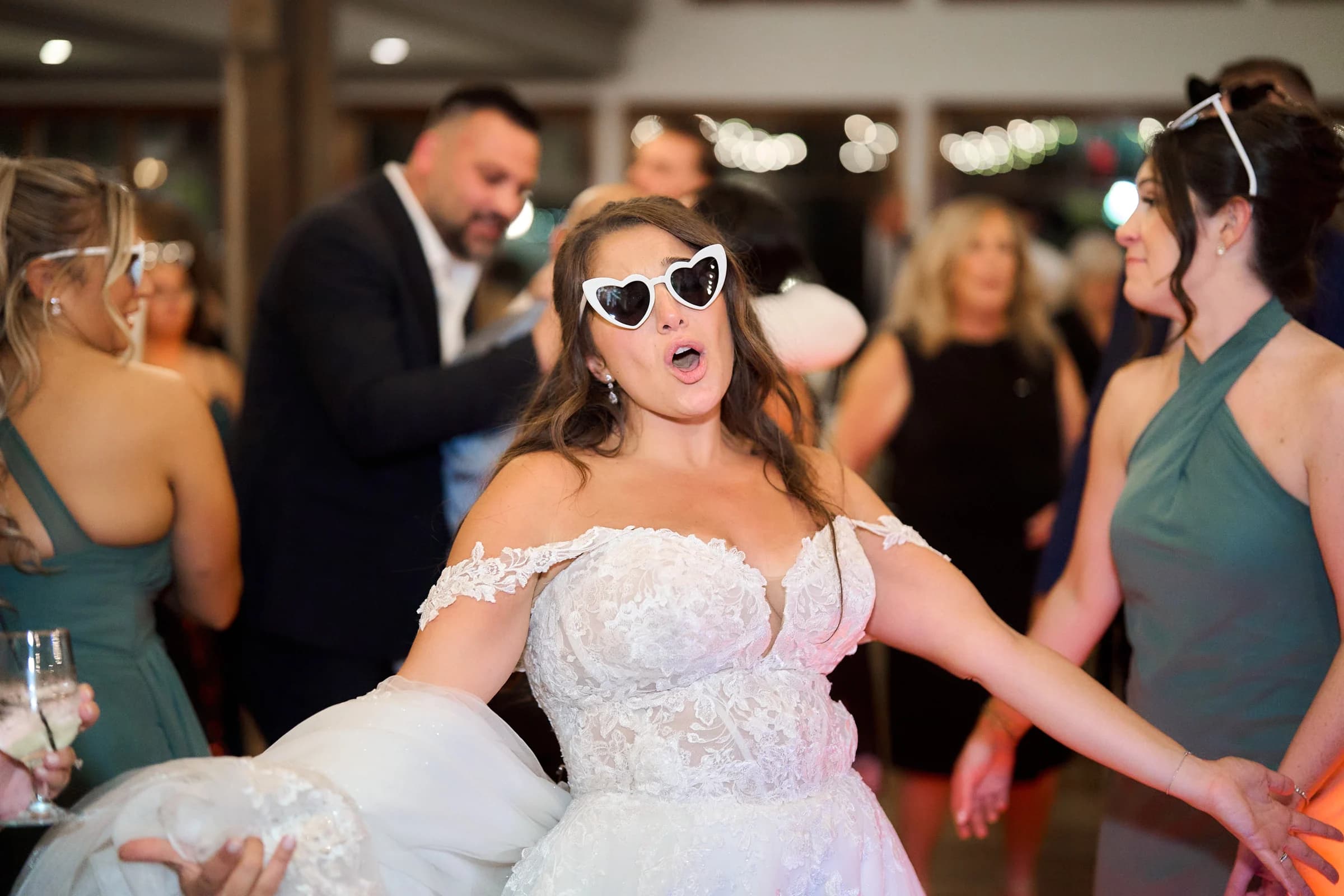 Amanda dancing in white heart-shaped sunglasses at the reception