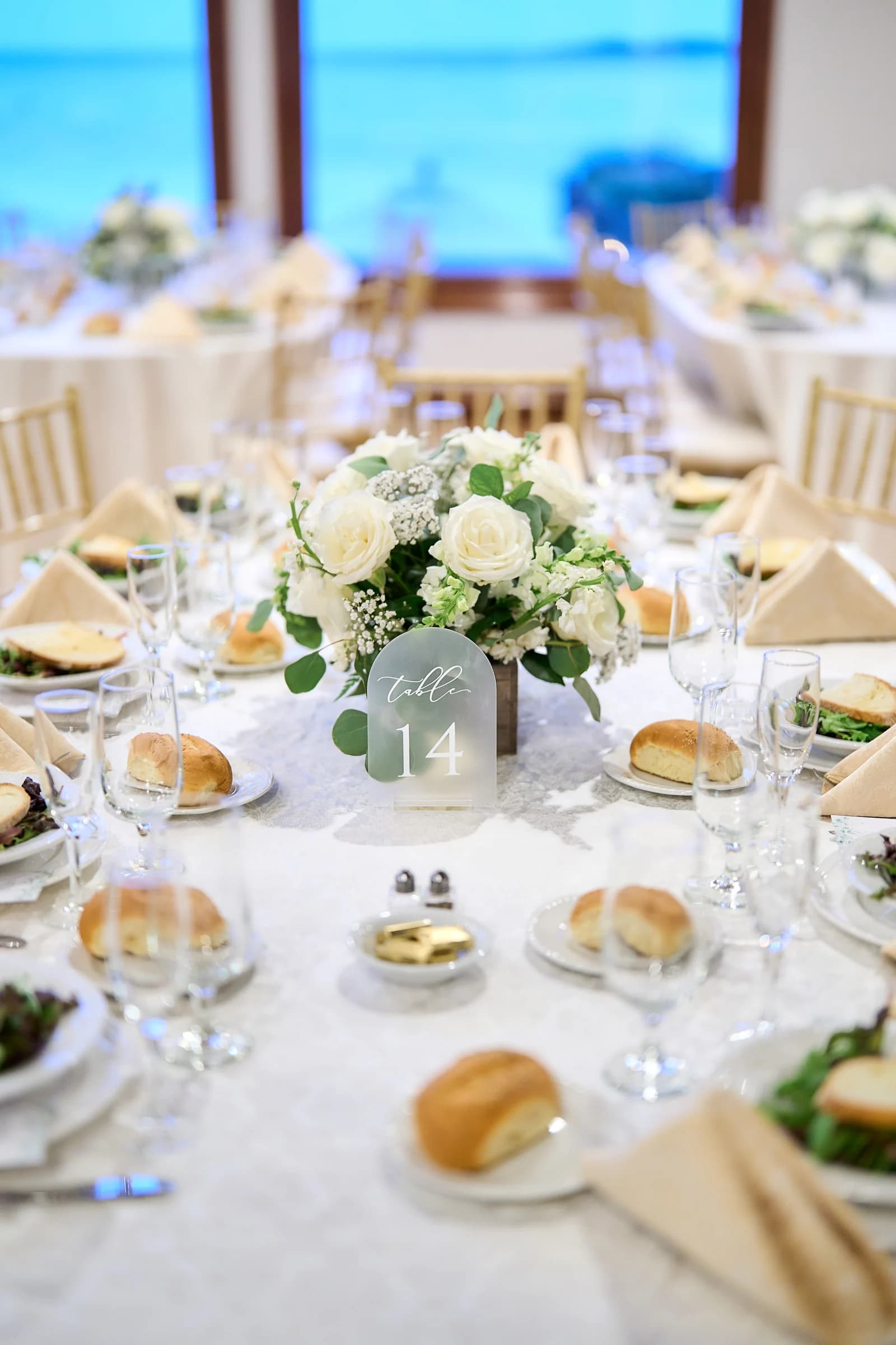 Table 14 set with white roses and the bay visible through the windows