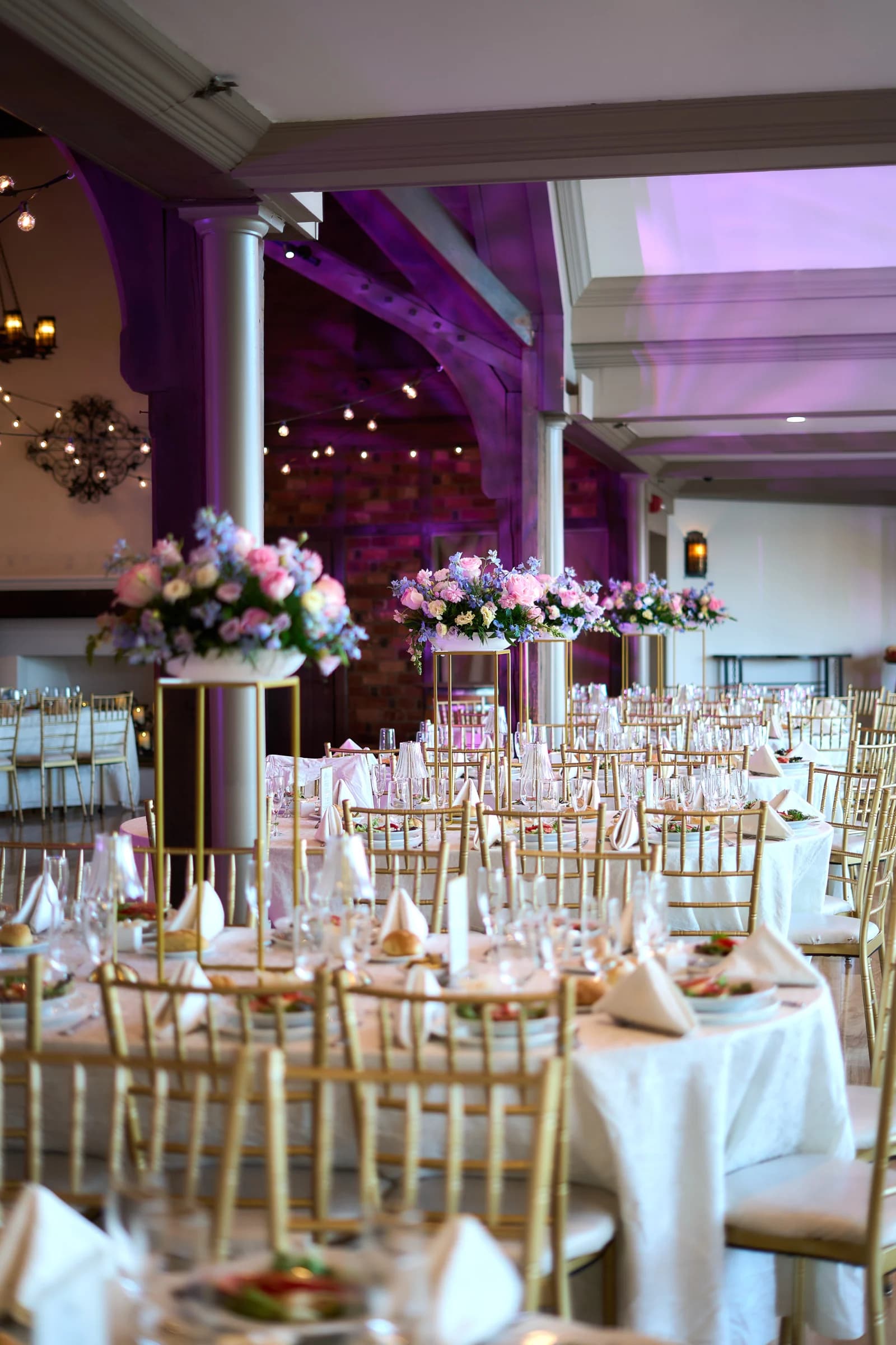 The Riviera ballroom set for Gabriela and Jakub's reception, with tall pastel centerpieces and gold chairs