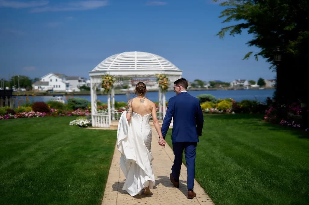 Garden grounds against a harbor estate, Bride and groom on the stone patio in front of the Riviera Waterfront Mansion facade