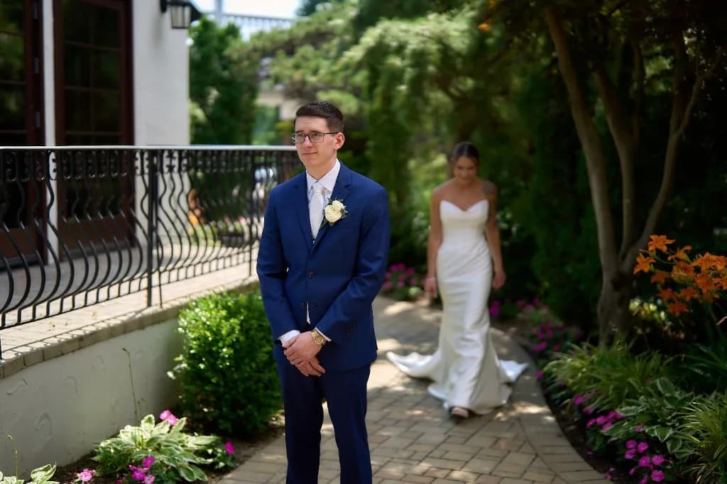 Golden hour portraits on the grounds, Bride and groom embrace on the lawn with the bay and flower beds behind them at the Riviera