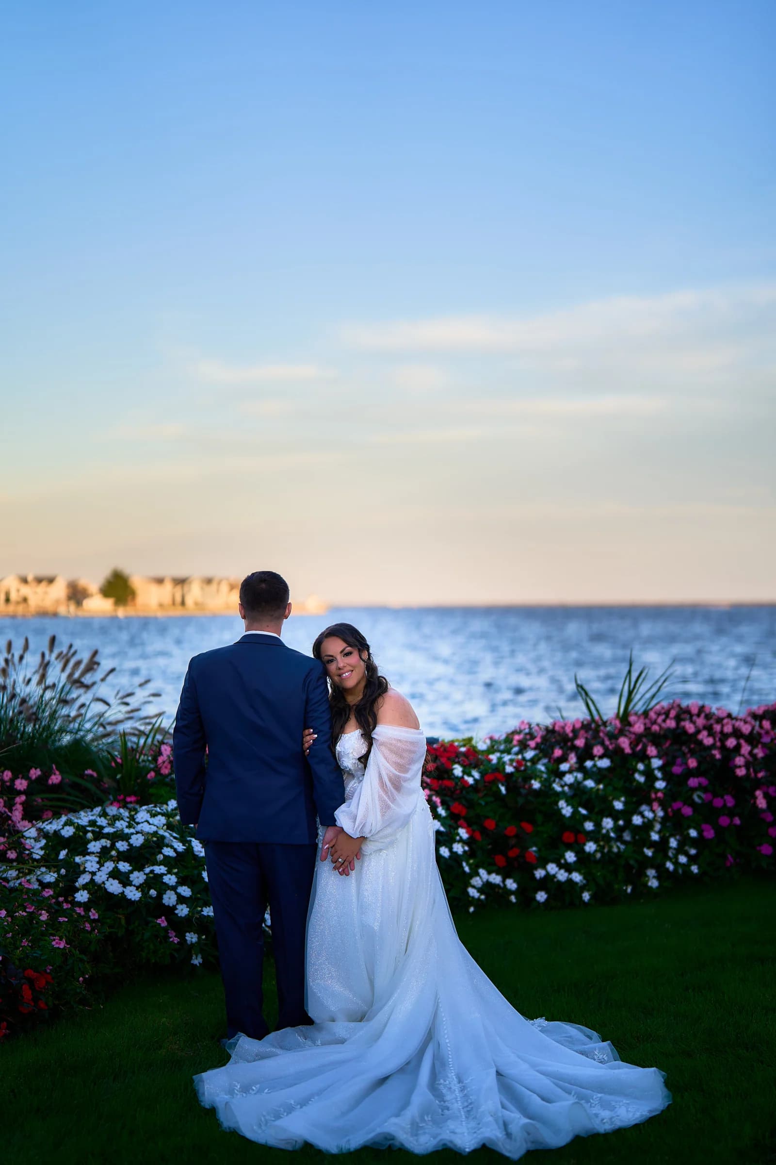Stephanie leaning into Peter beside the flower beds and the bay at the Riviera