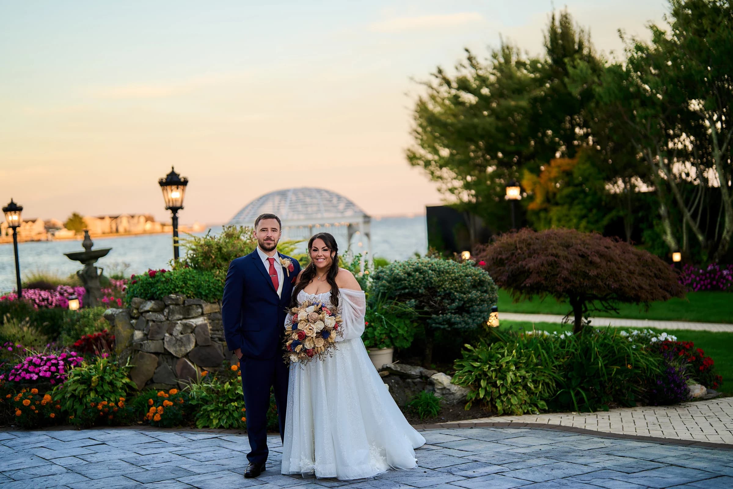 Chandelier light against open air ceremony, Stephanie and Peter on the waterfront patio at sunset, the Riviera gazebo behind them