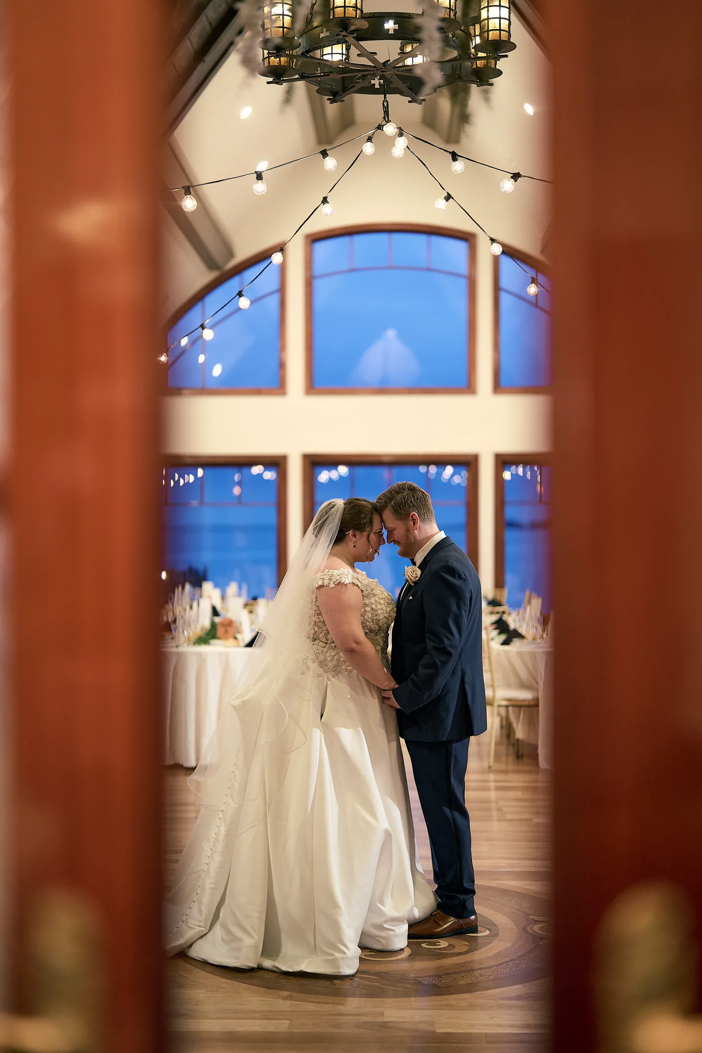 The dance floor filling up, Bride framed in a grand arched blue doorway at a Long Island venue