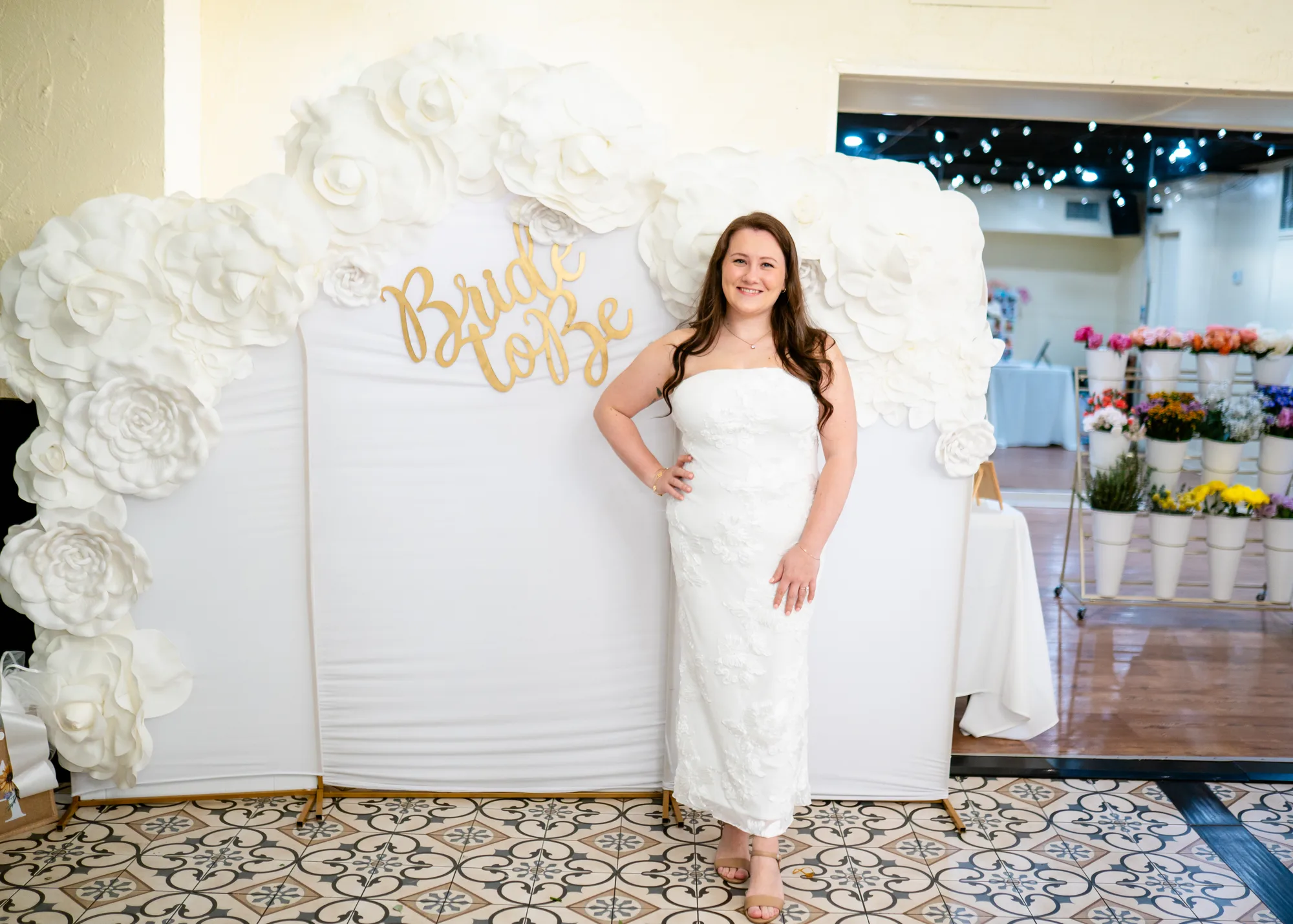 Bride to be beside a paper-flower wall at her bridal shower