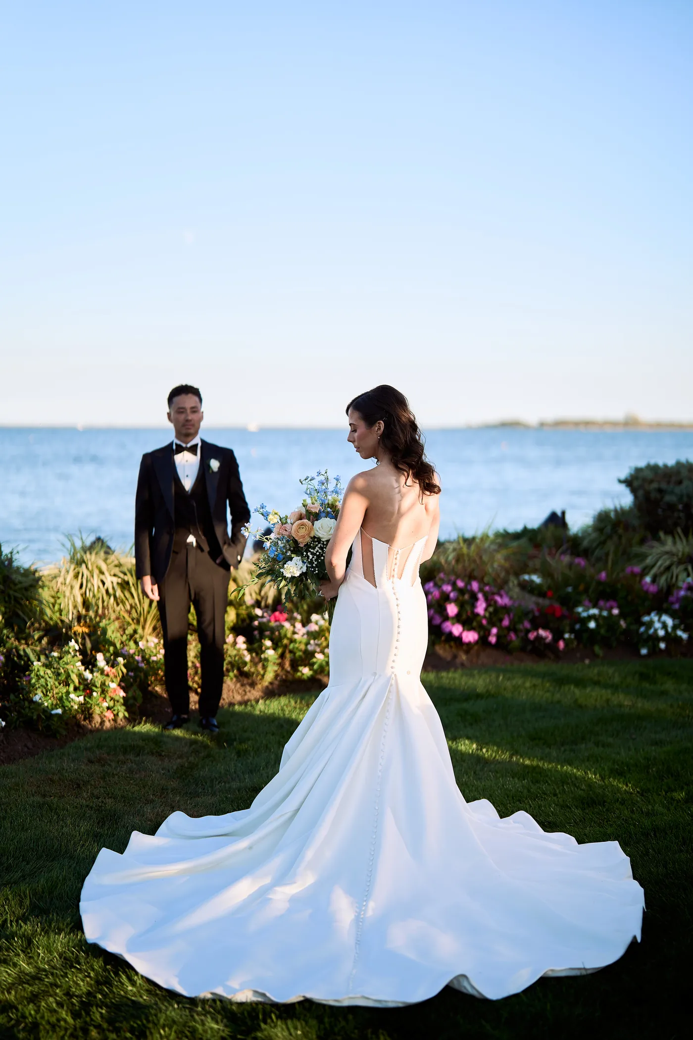 Editing a gallery on a calibrated screen, Bride with a sweeping gown train beside the water, the groom at her side